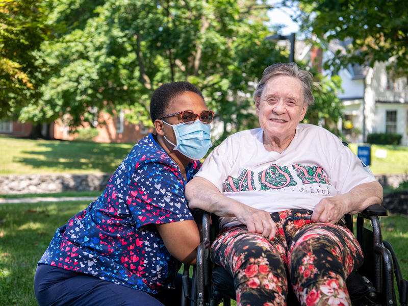 two women sitting in a wheelchair with a face mask